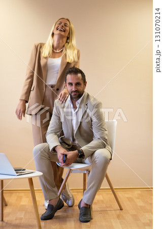 A business couple posing for a photograph together against a beige backdrop, capturing their professional partnership and creating a timeless image of unity and success. 131070214