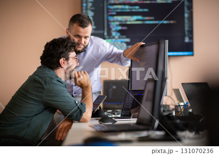 Programmers engrossed in deep collaboration, diligently working together to solve complex problems  131070236