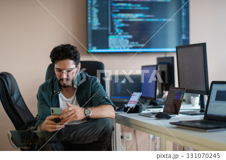 A programmer diligently testing smartphone applications A programmer diligently testing smartphone applications 131070245