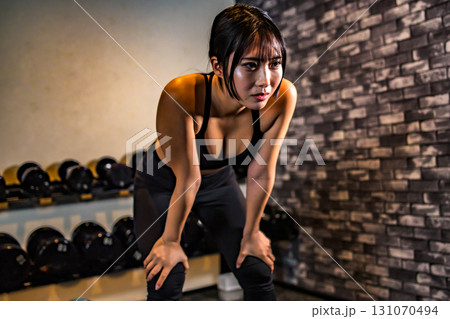 疲れて休憩する女性　疲労　ジムで運動するかっこいい女性　筋トレ女子　トリミングアップ 131070494