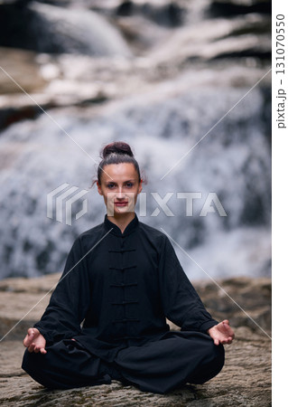 A woman sits in lotus pose, practicing yoga and tai chi under a tropical waterfall, meditating with calm strength and mindfulness, fully connected to the energy of nature, tranquility and inner A woman sits in lotus pose, practicing yoga and tai chi under a tropical waterfall, meditating with calm strength and mindfulness, fully connected to the energy of nature, tranquility and inner 131070550