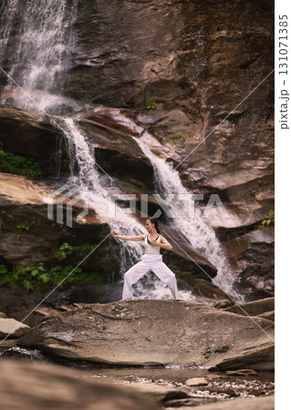 woman performing slow tai chi movements near a waterfall and river at sunset capturing harmony balance and fitness in nature woman performing slow tai chi movements near a waterfall and river at sunset capturing harmony balance and fitness in nature 131071385