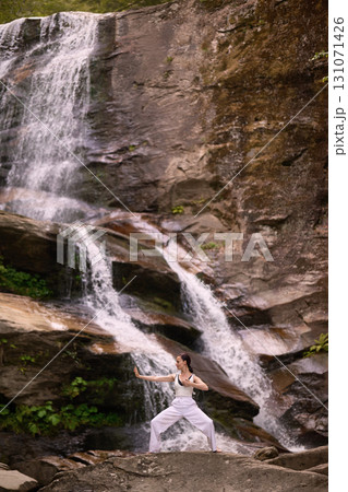 woman performing slow tai chi movements near a waterfall and river at sunset capturing harmony balance and fitness in nature woman performing slow tai chi movements near a waterfall and river at sunset capturing harmony balance and fitness in nature 131071426