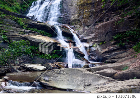 woman performing slow tai chi movements near a waterfall and river at sunset capturing harmony balance and fitness in nature 131071586