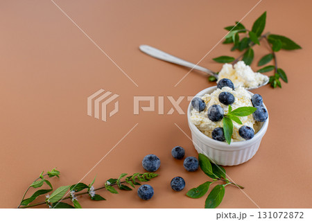 Seasonal composition cottage cheese blueberries and mint on a warm background Seasonal composition cottage cheese blueberries and mint on a warm background 131072872