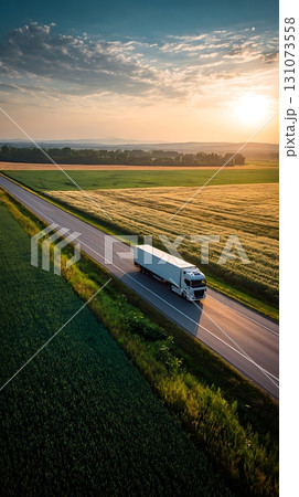 White SemiTruck on Highway at Sunset Beside Golden Fields Aerial View White SemiTruck on Highway at Sunset Beside Golden Fields Aerial View 131073558