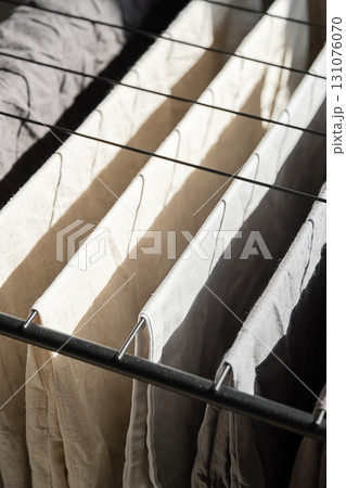 Drying clothes on laundry rack with sunlight creating shadows on the fabric. 131076070