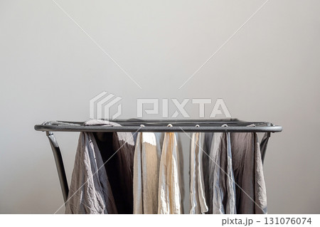Laundry drying on clothes horse, clean textile hanging on dryer rack, after washing process. 131076074