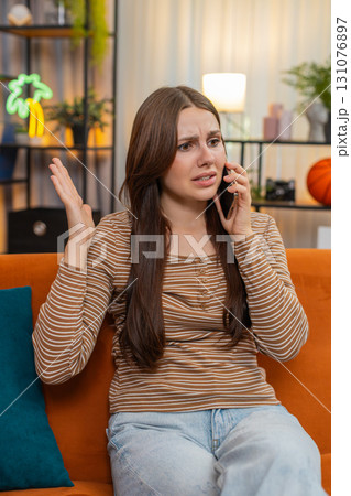 Young woman argues on smartphone frowns sharp hand moves raises voice and speaks fast in tense call 131076897