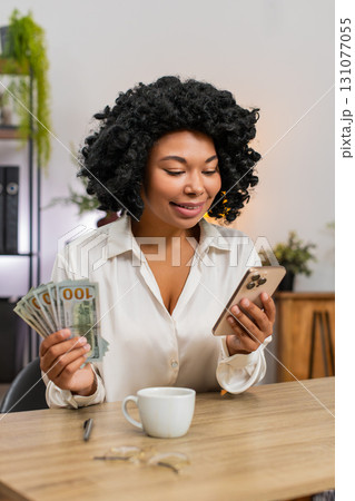 African American businesswoman happy holding dollars cash smartphone celebrates huge earnings budget African American businesswoman happy holding dollars cash smartphone celebrates huge earnings budget 131077055