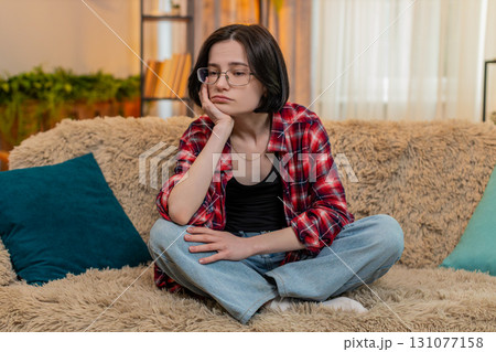 Woman sitting with sad face at home, thinking quietly about personal stress and difficult problem 131077158