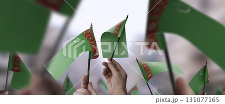 Turkmenistan flags in their hands on a blurred urban background 131077165