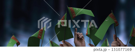 Turkmenistan flags in their hands on a blurred urban background 131077169