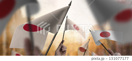 Japan flags in their hands on a blurred urban background Japan flags in their hands on a blurred urban background 131077177