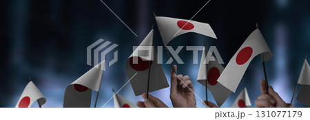 Japan flags in their hands on a blurred urban background Japan flags in their hands on a blurred urban background 131077179