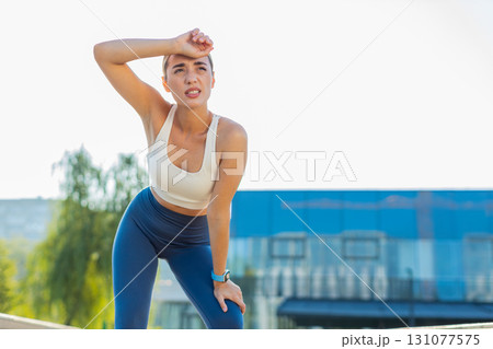 Tired young athlete woman jogger in sportswear resting after hard training in urban city park Tired young athlete woman jogger in sportswear resting after hard training in urban city park 131077575