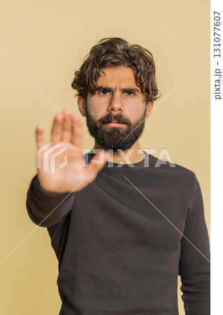 Hindu man says No hold palm in stop gesture, warning of finish prohibited access on beige background Hindu man says No hold palm in stop gesture, warning of finish prohibited access on beige background 131077607