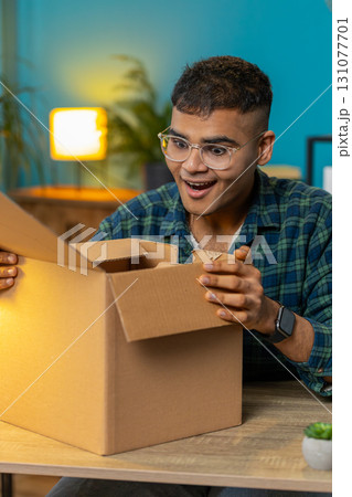Happy man shopper unpacking cardboard box delivery parcel online shopping purchase at home office Happy man shopper unpacking cardboard box delivery parcel online shopping purchase at home office 131077701