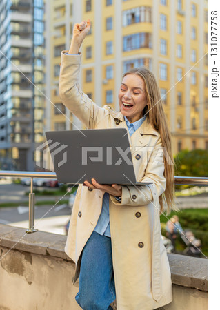 Overjoyed happy mature businesswoman working on laptop screaming in delight on downtown city street 131077758
