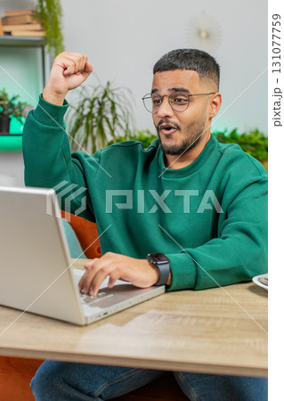 Amazed Indian man use laptop computer, receive good news message shocked by victory, celebrate win Amazed Indian man use laptop computer, receive good news message shocked by victory, celebrate win 131077759