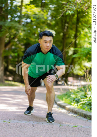 Asian athletic sport motivated runner man training, preparing to run race marathon in morning park 131077971