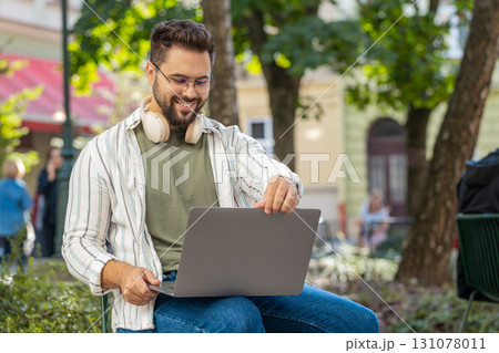 Caucasian young man freelancer working online distant job using laptop sitting on city town street 131078011