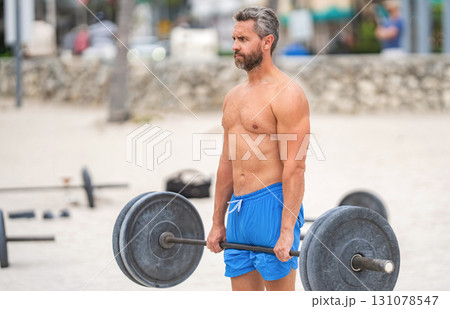 Sport athlete man with barbell, copy space. Healthy lifestyle barbell training. Mature man exercising with barbell outdoor. Man athlete lifting barbell. Muscular man do sport exercise. Gym workout Sport athlete man with barbell, copy space. Healthy lifestyle barbell training. Mature man exercising with barbell outdoor. Man athlete lifting barbell. Muscular man do sport exercise. Gym workout 131078547