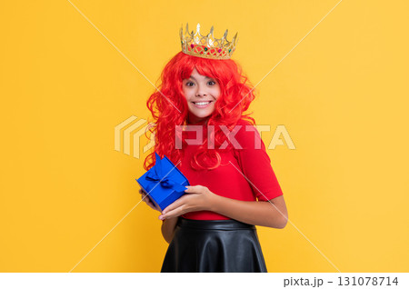 glad girl in crown with present box on yellow background 131078714