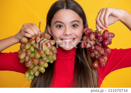 girl smile hold bunch of grapes on yellow background girl smile hold bunch of grapes on yellow background 131078716