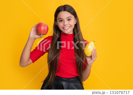 positive child hold apple and pear on yellow background 131078717