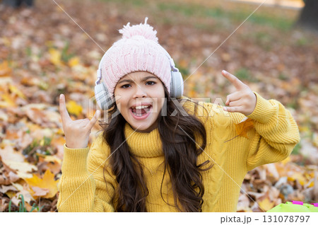 happy child in hat having fun while listening music in headphones outdoor in park, fun 131078797