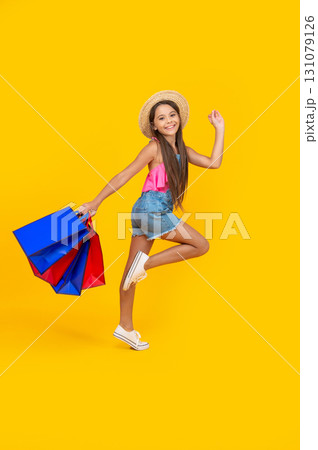 happy teen girl hurry up with shopping bags on yellow background. full length happy teen girl hurry up with shopping bags on yellow background. full length 131079126