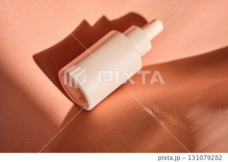 A bottle of serum in beige and peach tones. A bottle of serum in beige and peach tones. 131079282