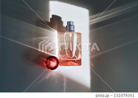 Pink perfume bottle on the light background in the rays of sun with highlights. 131079301