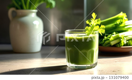 A refreshing green smoothie is presented in a glass with a celery garnish, surrounded by fresh celery stalks, promoting health and vitality in a modern kitchen setting. 131079400