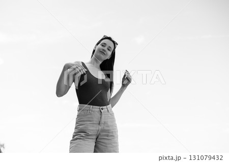 Young woman in casual outfit posing outdoors, black and white portrait Minimalistic background. A confident girl i modern outfit and confident pose. 131079432