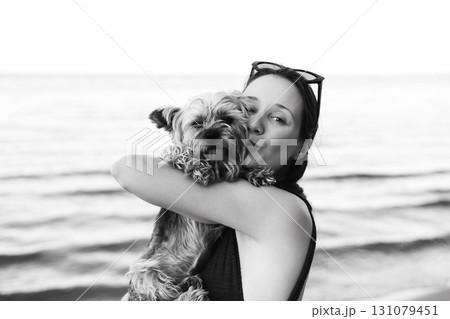 Tender portrait of young woman hugging and kissing small Yorkshire terrier dog. Emotional moment showing love, care and human animal bond. Tender portrait of young woman hugging and kissing small Yorkshire terrier dog. Emotional moment showing love, care and human animal bond. 131079451