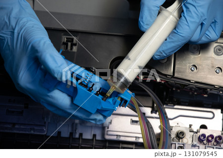 Top view of a technician using a vacuum cleaner to suck ink from a printer. Top view of a technician using a vacuum cleaner to suck ink from a printer. 131079545
