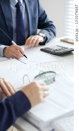Professional male accountant calculating taxes and analyzing financial data in office setting. Audit and taxes in business Professional male accountant calculating taxes and analyzing financial data in office setting. Audit and taxes in business 131079887