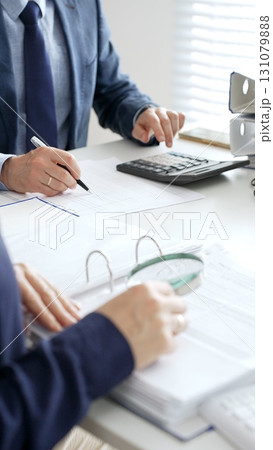 Professional male accountant calculating taxes and analyzing financial data in office setting. Audit and taxes in business 131079888