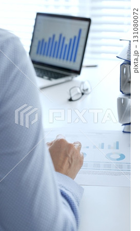 Business partners reviewing financial documents charts and diagrams , working collaboratively at white desk in office. Audit and taxes in business 131080072