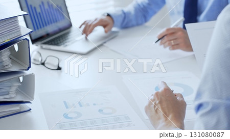 Group of accountants are analyzing financial reports and making notes while sitting at a white table, close up of a stack of blue folders full of paperwork. Audit and taxes in business Group of accountants are analyzing financial reports and making notes while sitting at a white table, close up of a stack of blue folders full of paperwork. Audit and taxes in business 131080087
