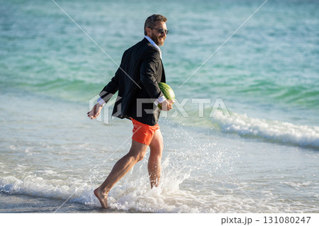 businessman in wet suit at the beach. Summer business dreams. Successful businessman on vacation. Businessman in suit with watermelon in sea. business man on summer vacation. summer gains 131080247