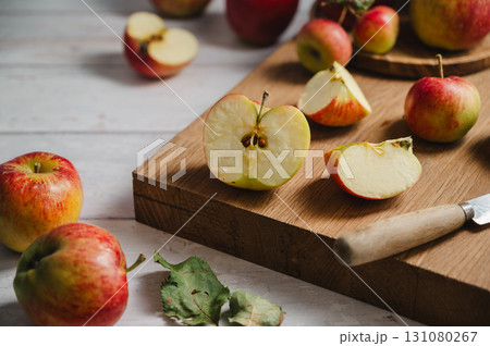Red apples, whole and sliced on a wooden cutting board, lifestyle, top view. Autumn abstract food background. 131080267