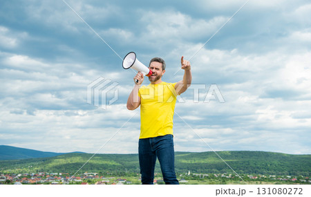 man in yellow shirt shout in loudspeaker on sky background. novelty man in yellow shirt shout in loudspeaker on sky background. novelty 131080272