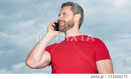 happy man has phone talk on sky background. man has phone talk outdoor. happy man has phone talk on sky background. man has phone talk outdoor. 131080275
