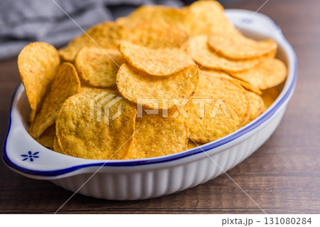 Crispy potato chips in bowl on wooden table. Crispy potato chips in bowl on wooden table. 131080284