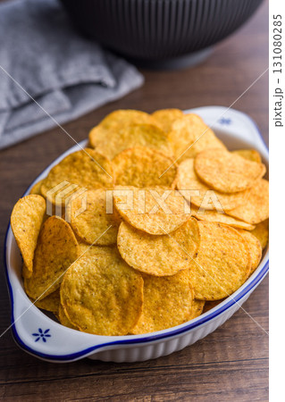Crispy potato chips in bowl on wooden table. Crispy potato chips in bowl on wooden table. 131080285