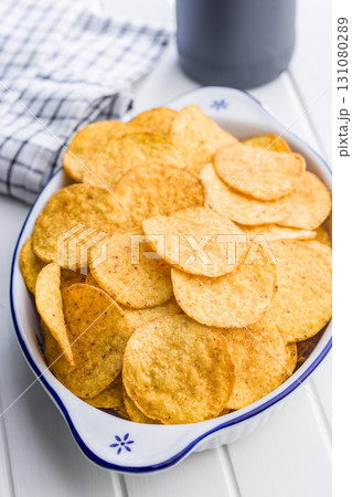 Crispy potato chips in bowl on white table. Crispy potato chips in bowl on white table. 131080289