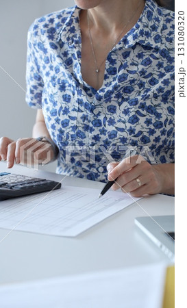 Businesswoman using calculator and filling tax form, calculating expenses and managing financial data in office. Audit and taxes in business Businesswoman using calculator and filling tax form, calculating expenses and managing financial data in office. Audit and taxes in business 131080320